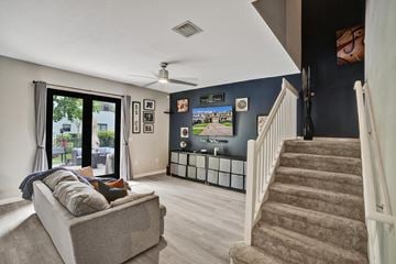 Miami apartment for rent - A living room with a grey couch and a staircase.