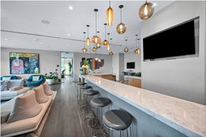 Miami apartment for rent - A modern kitchen with a bar area and a television mounted on the wall.