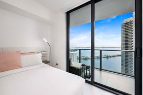 Miami apartment for rent - A bedroom with a large bed and a view of the city.