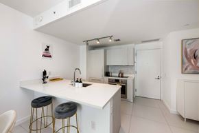 Miami apartment for rent - A kitchen with white cabinets and a white counter top.
