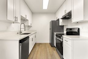 Ramona apartment for rent - A modern kitchen with white cabinets and black appliances.