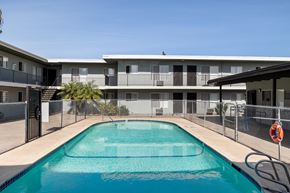 El Cajon apartment for rent - A swimming pool in front of a building with a fence around it.