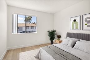 El Cajon apartment for rent - A bedroom with a large bed and a window overlooking a residential area.