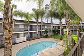 El Cajon apartment for rent - A pool surrounded by palm trees and apartment buildings.