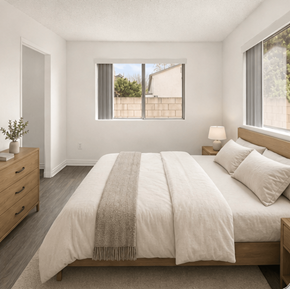 El Cajon apartment for rent - A bedroom with a large bed and a window overlooking a fence.