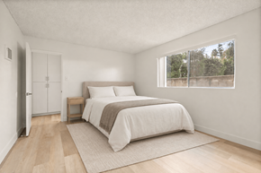 El Cajon apartment for rent - A bedroom with a bed, nightstand, and a window overlooking a fence.