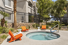 Las Vegas apartment for rent - A pool with a slide and chairs in front of a building.