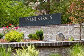 Gresham apartment for rent - A sign for Columbia Trails Apartment Homes is surrounded by plants and flowers.