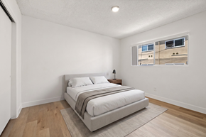 El Cajon apartment for rent - A bedroom with a large bed and a window showing a building outside.