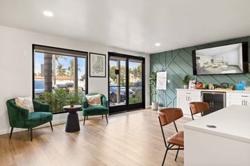 El Cajon apartment for rent - A modern living room with a green chair and a white kitchen in the background.