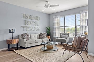 Round Rock apartment for rent - A living room with a couch, chair, and a rug in front of a wall with "Round Rock Texas" written on it.