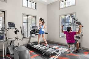 Las Vegas apartment for rent - A woman is running on a treadmill while a man is working out on a cable machine in a gym.