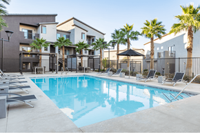 Henderson apartment for rent - A swimming pool surrounded by lounge chairs and palm trees.
