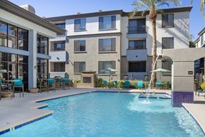 Phoenix apartment for rent - A swimming pool in front of a building with a palm tree.