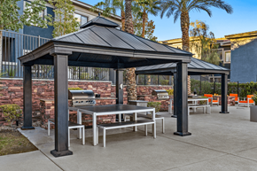 Henderson apartment for rent - A black gazebo with a table and chairs is surrounded by a brick wall and palm trees.