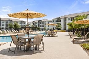 Sachse apartment for rent - A poolside area with chairs and umbrellas.
