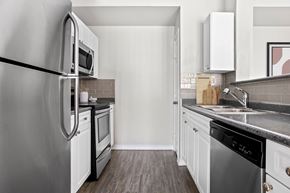 Fort Worth apartment for rent - A modern kitchen with a stainless steel refrigerator and white cabinets.