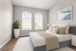 Fort Worth apartment for rent - A bedroom with a large bed and a potted plant.