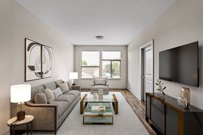 Nashville apartment for rent - A modern living room with a grey sofa, a glass coffee table, and a flat-screen TV mounted on the wall.