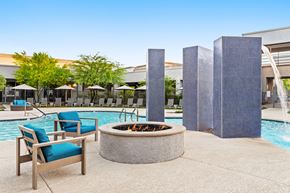 Phoenix apartment for rent - A poolside area with a fire pit, chairs, and umbrellas.