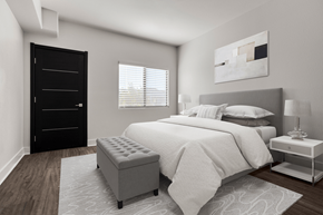 Henderson apartment for rent - A modern bedroom with a large bed, a black wardrobe, and a white nightstand.
