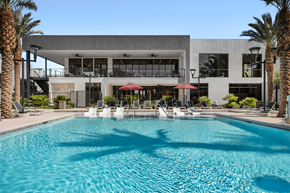 Henderson apartment for rent - A large swimming pool in front of a modern building with palm trees around it.