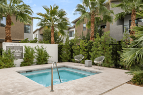 Las Vegas apartment for rent - A pool surrounded by palm trees and chairs.