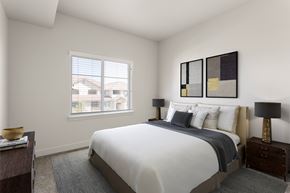 Stockton apartment for rent - A bedroom with a large bed and a window overlooking a residential area.