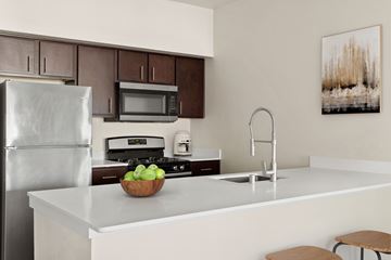 Stockton apartment for rent - A modern kitchen with a refrigerator, microwave, oven, sink, and a bowl of apples on the counter.