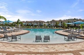Jacksonville apartment for rent - A large swimming pool surrounded by lounge chairs and umbrellas.