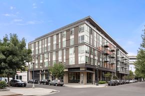 Portland apartment for rent - A modern multi-story building with a parking lot in front.