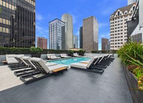 Los Angeles apartment for rent - A rooftop pool area with lounge chairs and a city skyline in the background.