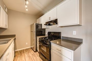 Santa Clarita apartment for rent - A kitchen with white cabinets and a black stove top oven.