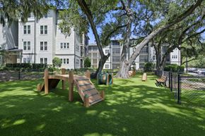 Tampa apartment for rent - A playground with a slide and a wooden bench is in the foreground of a grassy area.