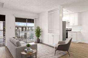 El Cajon apartment for rent - A living room with a grey couch, a brown armchair, a coffee table, and a potted plant.