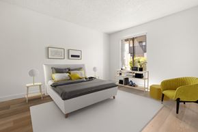 El Cajon apartment for rent - A bedroom with a white bed and yellow chair.
