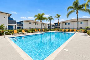 Lakeside apartment for rent - A large swimming pool surrounded by palm trees and lounge chairs.