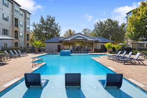 San Antonio apartment for rent - A swimming pool surrounded by lounge chairs and a pavilion in the background.