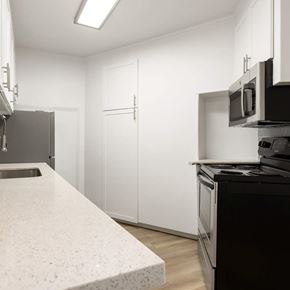 San Diego apartment for rent - A kitchen with white cabinets and black appliances.