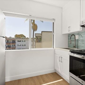 San Diego apartment for rent - A kitchen with white cabinets and a stove top oven.