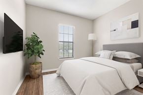 Jacksonville apartment for rent - A bedroom with a large bed and a flat screen TV mounted on the wall.