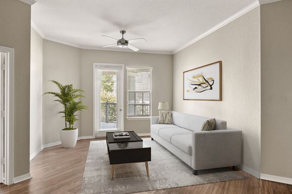 Jacksonville apartment for rent - A living room with a grey couch, a coffee table, a plant, and a painting on the wall.
