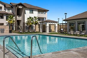 Stockton apartment for rent - A swimming pool in front of a building with palm trees.