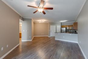 Irving apartment for rent - A spacious room with a ceiling fan and hardwood flooring.