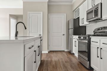 Austin apartment for rent - A kitchen with white cabinets and a black fridge.