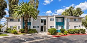 Ramona apartment for rent - A building with a green door and a palm tree in front.