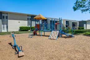 Lakewood apartment for rent - A playground with a blue swing set and a yellow umbrella.