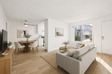 El Cajon apartment for rent - A living room with a grey couch, a wooden dining table with chairs, a television, and a rug.
