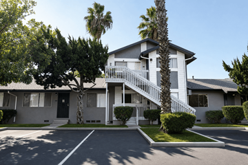 El Cajon apartment for rent - A white two-story house with a balcony and a palm tree in front.