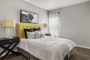 Phoenix apartment for rent - A bedroom with a yellow headboard and a white bedspread.